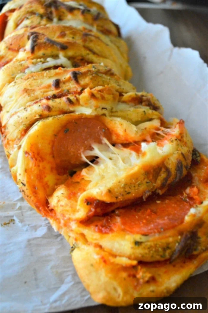 Pizza Monkey Bread 5 A section of freshly baked pull apart pizza bread, showing the rich melted cheese and pepperoni inside, ready for a family meal.