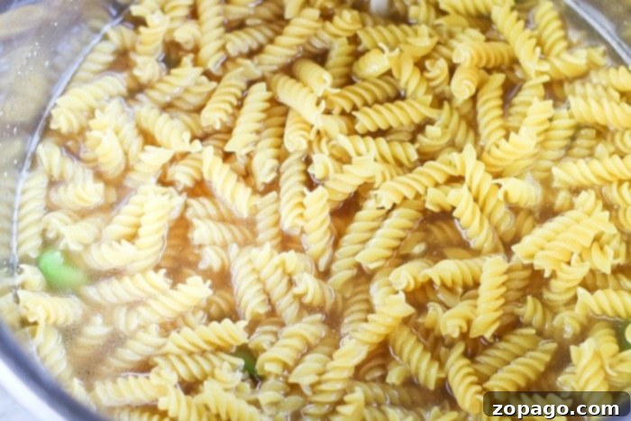 Instant Pot Philly Cheesesteak Pasta 8 Perfectly cooked rotini pasta in Instant Pot with rich meat sauce and melted cheese, ready to be scooped.