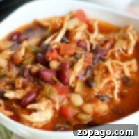 Hearty Instant Pot Chicken Chili 6 A bowl of white bean chicken chili with beans and vegetables sits invitingly on a tablecloth, effortlessly prepared in an Instant Pot.