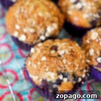 Wild Huckleberry Muffins 8 Close-up of huckleberry muffins with crumb topping on a cooling rack, showcasing the easy muffin recipe over a colorful patterned cloth.