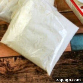 Clear bags of white powder, resembling homemade yellow cake mix, rest on a wooden surface near a box.