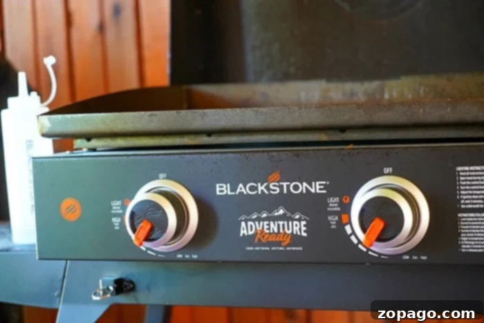 Blackstone 22-Inch Griddle 3 Close-up of a Blackstone Adventure Ready griddle with two control knobs, set outdoors near a wooden surface. This Blackstone 22 model is perfect for alfresco cooking adventures.