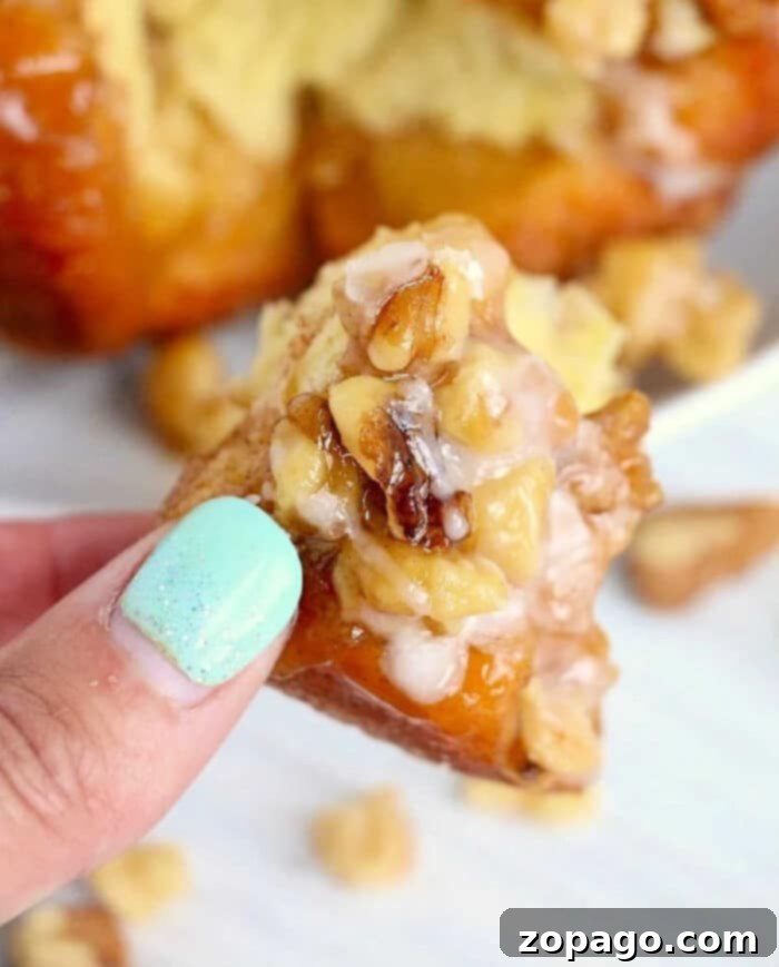 Easy Air Fryer Monkey Bread 10 A top-down view of monkey bread being prepared in an air fryer pan, showing the biscuit pieces coated and drizzled with sauce before cooking.