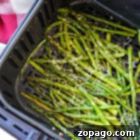 Asparagus in the air fryer topped with grated cheese.