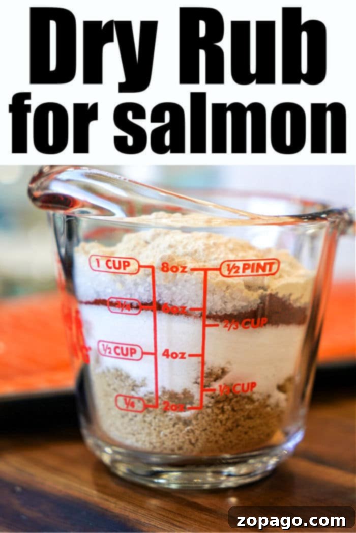 Ultimate Salmon Spice Blend 9 Measuring cup with layered ingredients for a flavorful salmon dry rub on a wooden surface.
