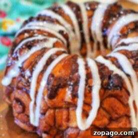 A glazed Rhodes monkey bread with icing drizzled, placed on a wooden board.