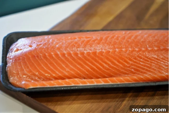 Ultimate Baked Salmon 5 A large, vibrant salmon fillet, perfectly seasoned with a generous amount of dry rub, is laid out on a baking sheet, ready for the oven. This preparation promises the best baked salmon.