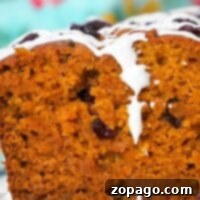 Close-up of sliced pumpkin cranberry bread with white icing drizzled on top, showcasing the moist interior.