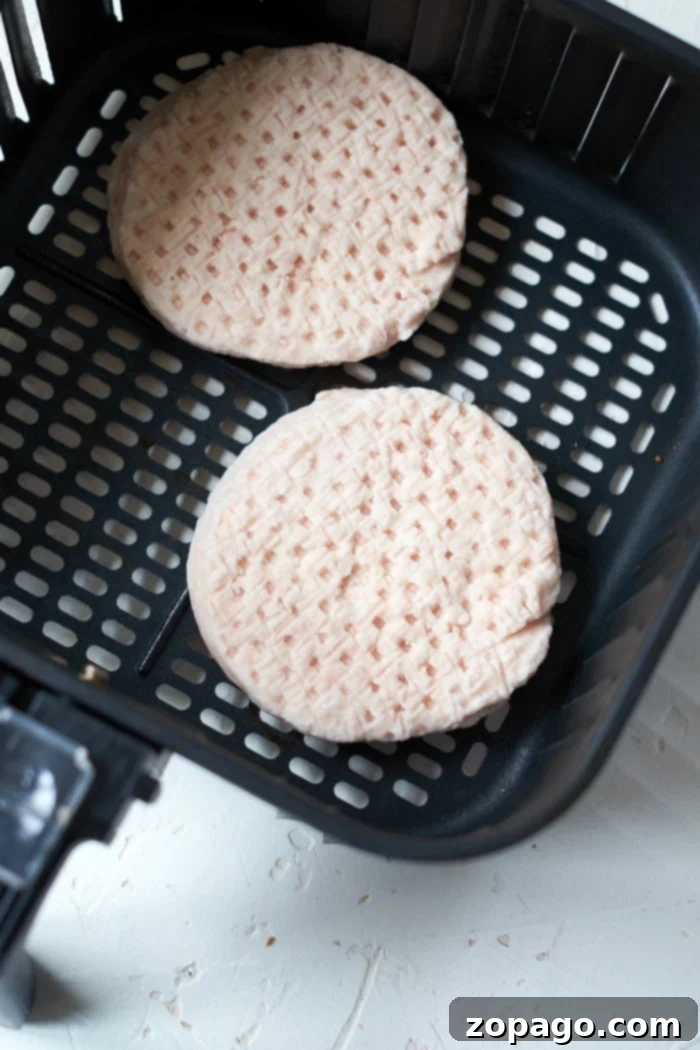 Perfect Air Fryer Frozen Turkey Burgers 3 Two frozen turkey burger patties nestled in an air fryer basket, awaiting the perfect cook.