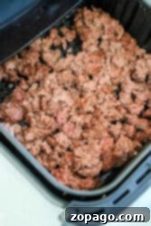 Cooked air fryer ground beef in a black air fryer basket, showing its lean and browned texture.