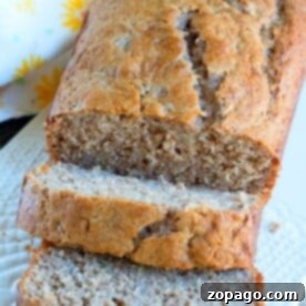 Surprising Mayonnaise Banana Bread 9 A sliced loaf of banana bread with mayonnaise on a white plate, complemented by a floral napkin in the background.