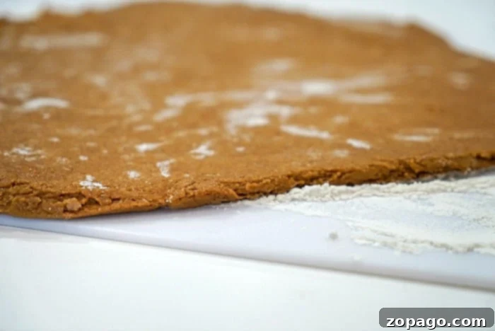Easy Cake Mix Gingerbread Cookies 6 Rolled-out gingerbread cookie dough, meticulously cut into festive shapes, rests on a floured surface, ready for transfer to the baking sheet and eventual baking.