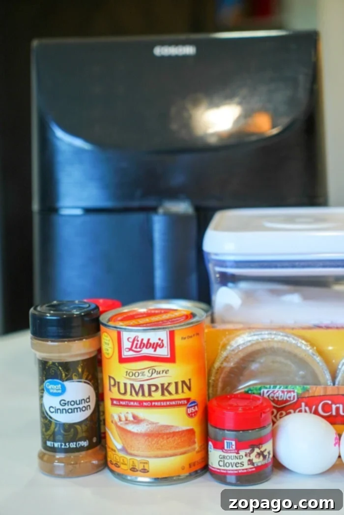 Bite-Sized Pumpkin Pie Delights 3 Air fryer basket filled with mini pumpkin pies in foil cups, showing their golden-brown edges.
