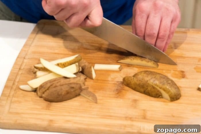 Perfect Bake Time for Fries at 400F 4 A person expertly slicing potatoes into sticks on a wooden cutting board, preparing for delicious homemade french fries.