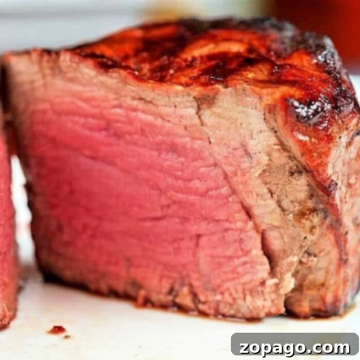 Air Fryer Filet Mignon Perfection 2 Perfectly cooked air fryer filet mignon with a seared crust and pink center, ready to be sliced.