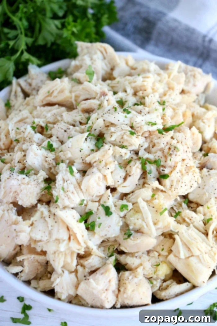 From Freezer to Feast Slow Cooker Chicken 2 Chopped cooked chicken, seasoned with herbs and pepper, served in a white bowl, prepared from frozen in a Crockpot.