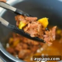 Tongs hold tender shredded Mississippi roast with yellow peppers above a simmering Instant Pot full of rich broth.