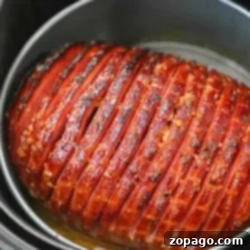 A perfectly glazed air fryer ham with scored lines, expertly cooked and nestled inside the pot.