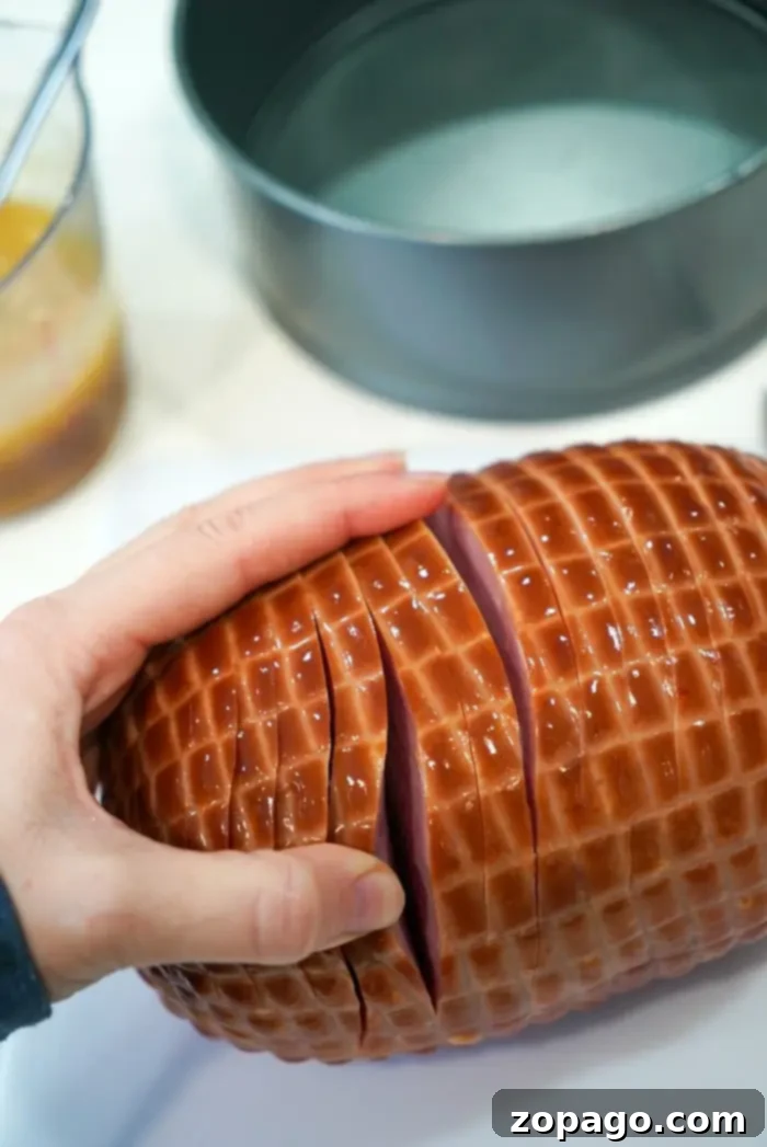 Crispy Air Fryer Ham 8 A hand slices an air fryer ham with a grid pattern on its surface.