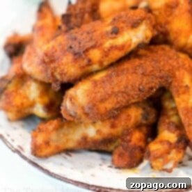 Effortless Cosori Air Fryer Creations 14 A plate filled with crispy, golden brown dry rub air fryer wings stacked on top of each other. The wings are seasoned with visible spices and appear to be freshly cooked. The edges of the plate are slightly visible, making this recipe a feast for both the eyes and taste buds.