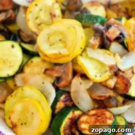 Effortless Cosori Air Fryer Creations 16 A dish featuring air fryer vegetables, including sautéed yellow squash, zucchini, mushrooms, and onions. The sliced veggies are seasoned to perfection with a delightful browning from cooking. This colorful mixture is beautifully presented on a plate.