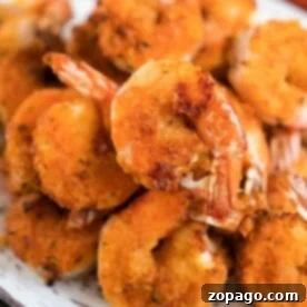Effortless Cosori Air Fryer Creations 7 A plate of golden-brown, crispy air fryer fried shrimp stacked in a pile, showcasing a crunchy texture with visible seasonings.