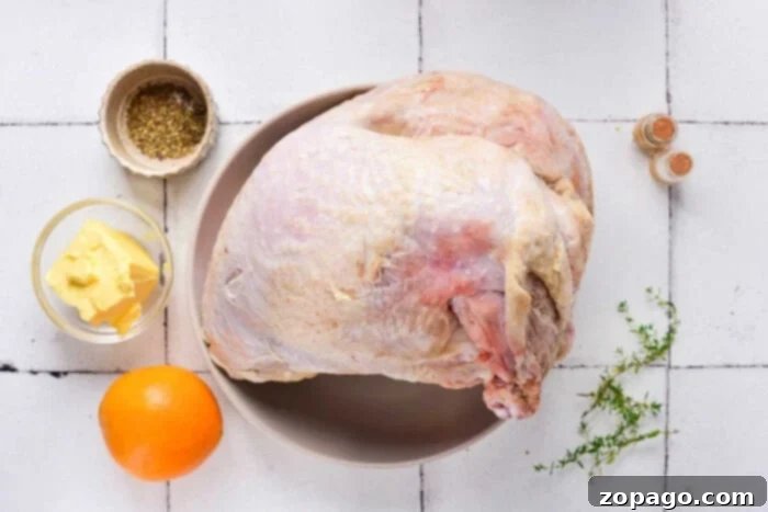 Tender Slow Cooker Turkey Crown 3 Raw turkey breast on a plate with butter, spices, an orange, and herbs awaits transformation into a delightful dish. Discover enticing slow cooker turkey breast recipes to infuse these fresh ingredients with flavor effortlessly on your stovetop.