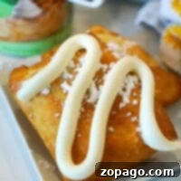 Pastry topped with icing and powdered sugar sits elegantly on a plate, accompanied by a can of apple filling in the background. Nearby, air fryer dumplings await their turn, promising a crispy and delightful contrast to the sweet treats.