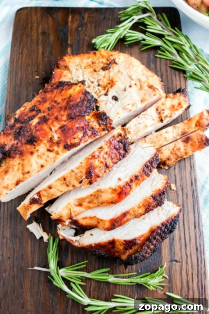 Crispy Air-Fried Turkey Breast 10 Sliced roasted turkey breast on a wooden cutting board, garnished with sprigs of rosemary, brings to mind the juicy tenderness of air fryer turkey breast.