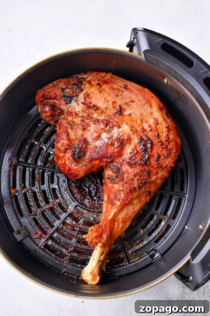 Crispy, golden-brown chicken leg quarters in an air fryer basket, ready to be served.