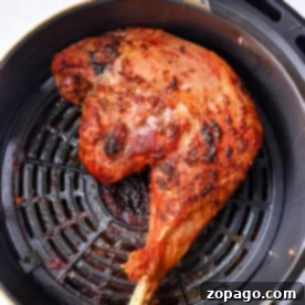 Crispy chicken leg quarters in an air fryer basket, perfectly cooked.