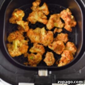 Golden-brown air fryer cauliflower wings nestled perfectly in the basket.