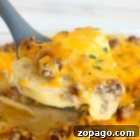Versatile Ground Beef Recipes 7 Close-up of a cheesy ground beef casserole with potatoes being served with a spatula.