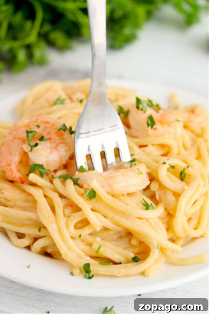 Instant Pot Shrimp Magic 8 Fork in creamy shrimp pasta garnished with parsley on a white plate, reminiscent of the flavors of instant pot bang bang shrimp.