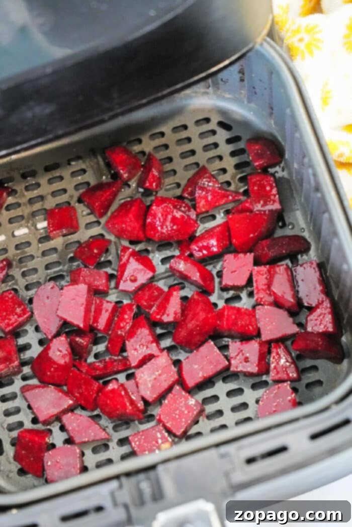 Crispy Air Fryer Beets 8 Diced red beets placed in an air fryer basket, ready for cooking. These air fryer beets are spread out evenly across the perforated surface.
