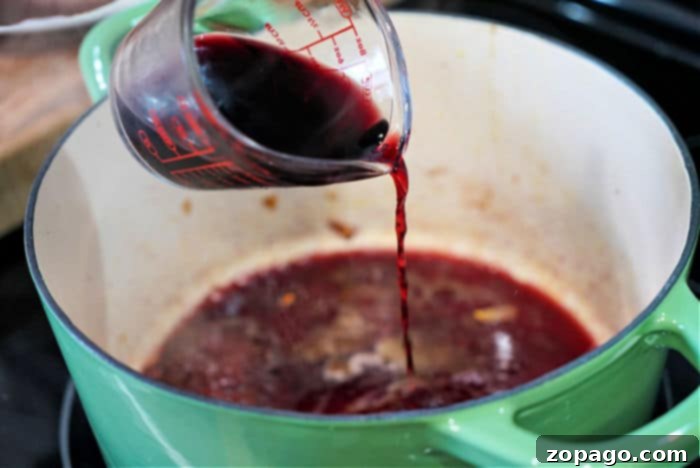 The Ultimate Dutch Oven Roast 6 The process of deglazing a Dutch oven with red wine, scraping up flavorful browned bits from the bottom of the pot.