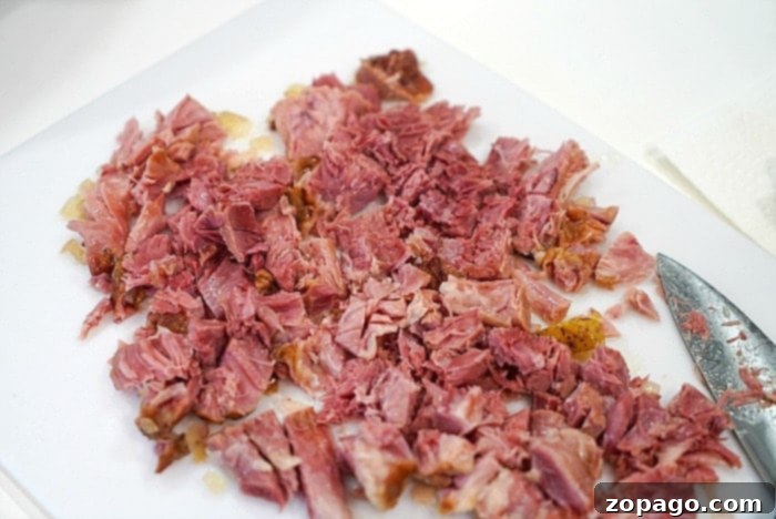 Hearty Instant Pot 15 Bean Soup 3 Finely chopped ham, ready to be added to a hearty bean soup, sits on a white cutting board next to a chef's knife.