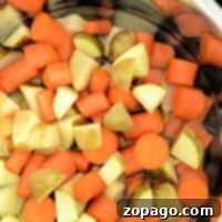 Chopped carrots and potatoes simmer gently in an Instant Pot, transforming the water into a fragrant, savory broth.