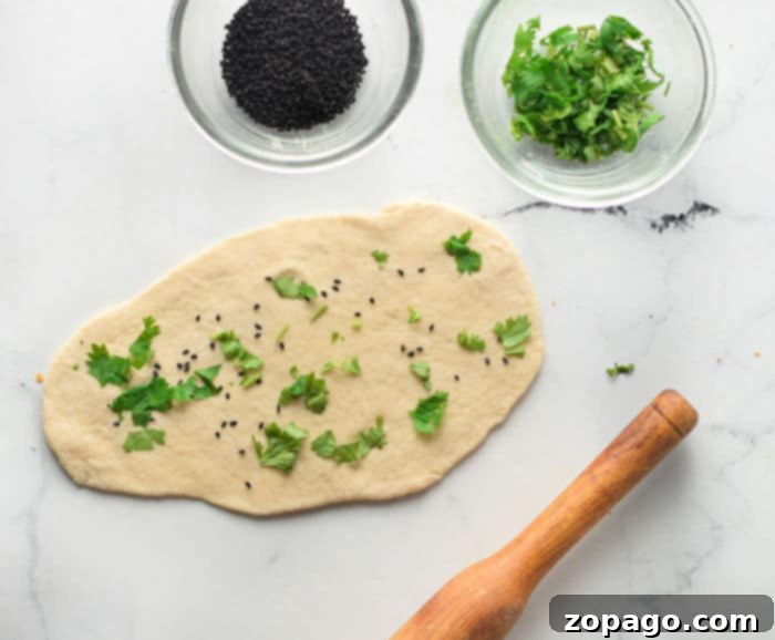 Homemade Air Fryer Naan Bread 5 Hand rolling out naan dough into an oval shape on a wooden board with a rolling pin.