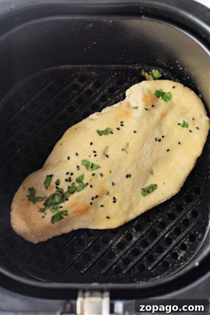 Homemade Air Fryer Naan Bread 6 Several pieces of cooked air fryer naan bread stacked on a plate, ready to be served.