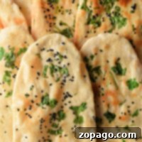 Close-up of naan bread, part of a homemade naan recipe, sprinkled with black seeds and fresh cilantro.