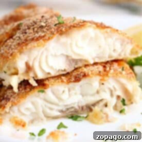 Two pieces of baked, breaded white fish fillets—similar to air fryer catfish—garnished with chopped parsley on a white plate.