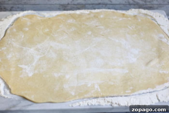 Luscious Homemade Blueberry Sweet Rolls 6 A rectangular sheet of sweet bread dough, evenly rolled out on a floured surface, ready for filling and shaping.