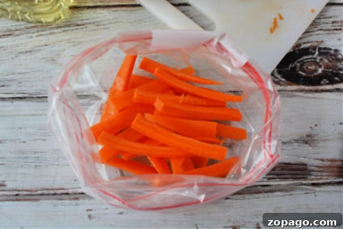 Sweet and Crispy Air Fryer Carrot Sticks 4 Carrot fries arranged in an air fryer basket before cooking