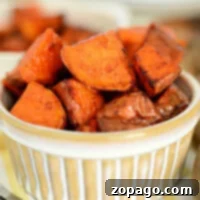 Golden-brown roasted sweet potato cubes, perfectly seasoned and nestled in a ceramic dish, achieve their crisp perfection with the help of an air fryer.