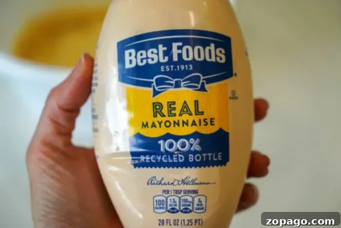Copycat Bang Bang Shrimp Sauce 3 A person holds a 20 fl oz bottle of Best Foods Real Mayonnaise, labeled "100% Recycled Bottle." Perfect for crafting the ultimate bang bang shrimp sauce, this mayo offers 100 calories per tablespoon serving and nutrition facts right on the label.