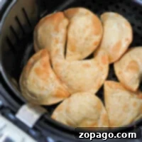 Crispy Air Fryer Pierogies From Frozen 8 Golden brown frozen pierogies in an air fryer basket, lightly seasoned with pepper.