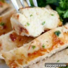 Close-up of chicken slices on a fork, expertly reheated in an air fryer for perfect crispness, garnished with herbs. A side of greens adds a vibrant touch in the background.