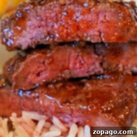 Easy Air Fryer Cube Steak 10 Three pieces of cube steak, cooked to perfection in an air fryer, stacked on a bed of fluffy white rice.