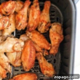 Cooked lemon pepper chicken wings in an air fryer basket.